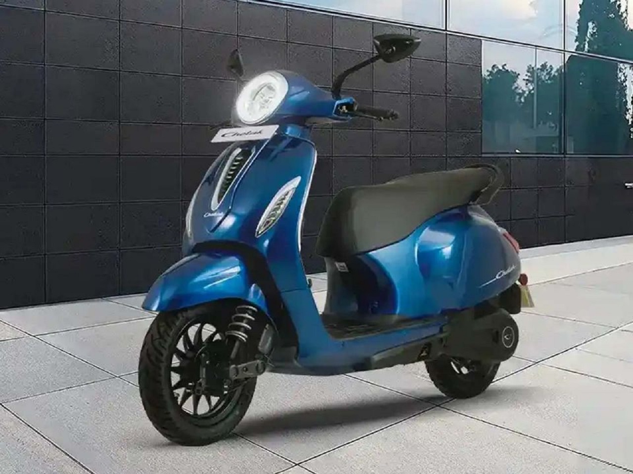 Scooter azul estacionada em um ambiente moderno, com destaque para seu design elegante e rodas robustas.