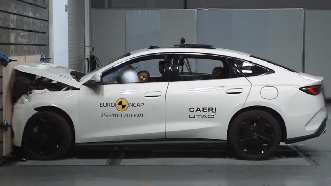Teste de colisão Euro NCAP com veículo branco, demonstrando segurança automotiva com bonecos de teste.