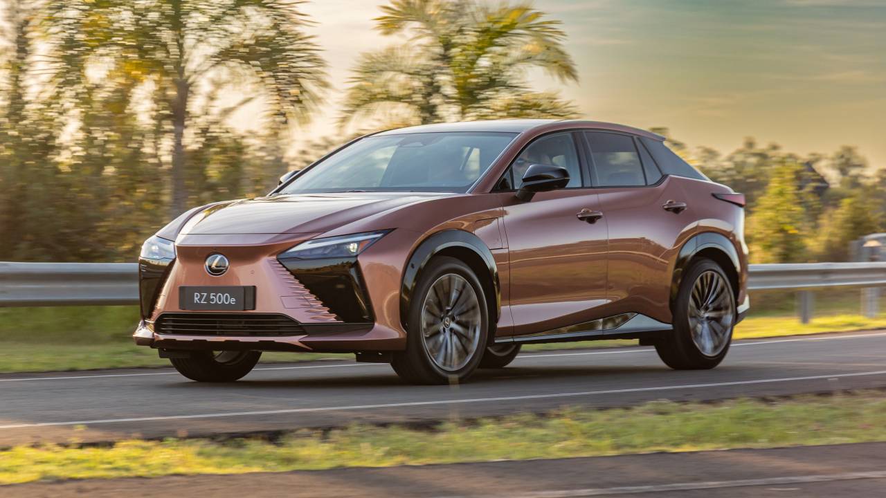 SUV Lexus RZ 500e em movimento, com design moderno e background de natureza ao pôr do sol.